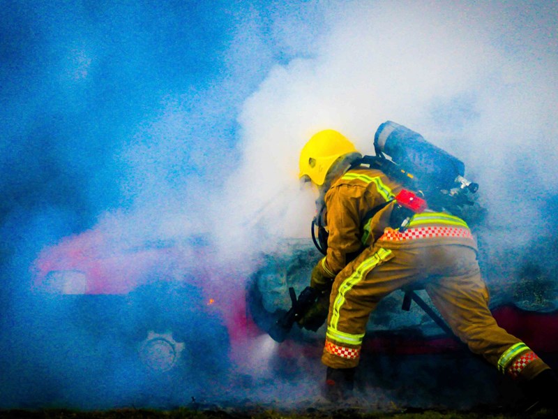 Firefighter sawing into side of car