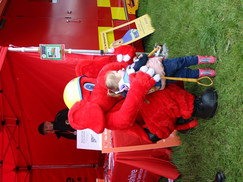 Staffordshire Fire and Rescue mascot, Welephant hugging a female child at County Show 2024.