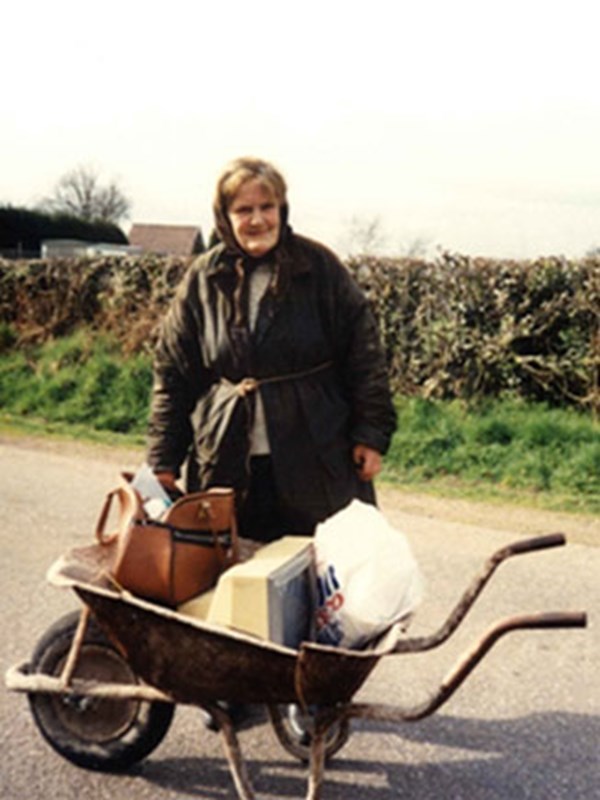 Elderly lady with wheelbarrow full of belongings