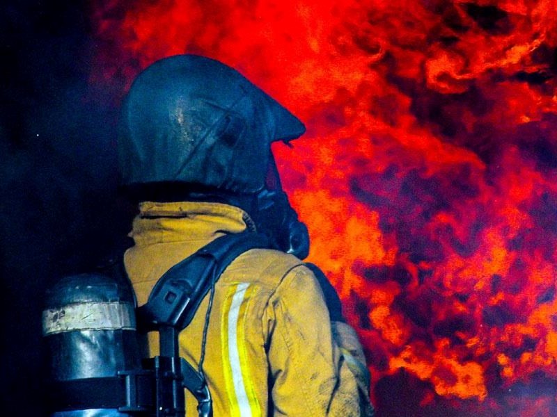 Firefighter in breathing apparatus tackling red flames