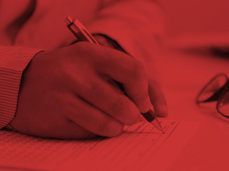 Person writing on paper with pen