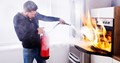 Man putting out oven fire with fire extinguisher 