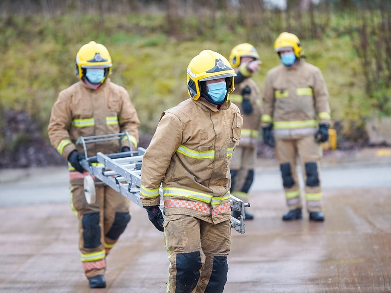 Two firefighters carrying a ladder