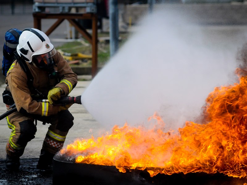 Station manager extinguishing a fire with a hose